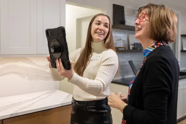 a young woman holding up a tablet and older woman smiling at a kitchen cabinet