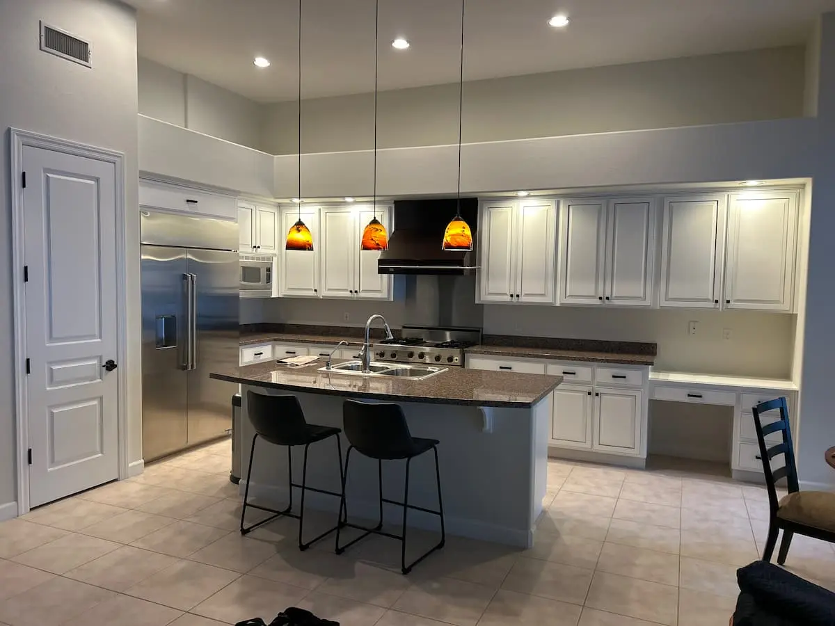 outdated kitchen with white cabinets and brown stone countertops