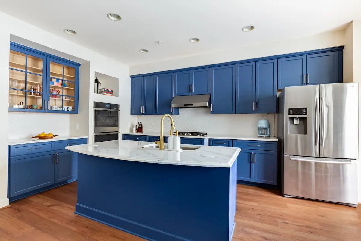 Updated kitchen with white countertops, blue cabinets, and blue island