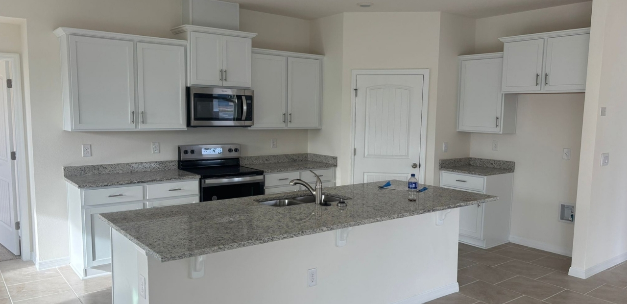 Builder-grade kitchen in Kissimmee FL with basic cabinets and standard layout