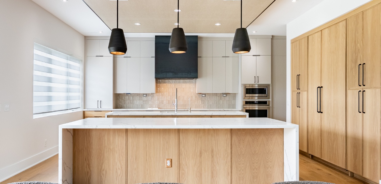 Warm contemporary kitchen in Lake Nona FL with white oak and gray cabinets, double island, stacked cabinets, and panel-ready refrigerator