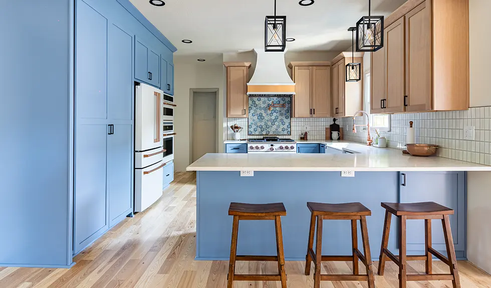 full view of kitchen with blue and wood custom cabinets and white appliances