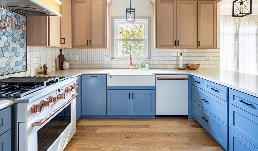 close up of the inside of kitchen with custom wood and blue cabinets with white appliances and farmhouse sink with gold accents