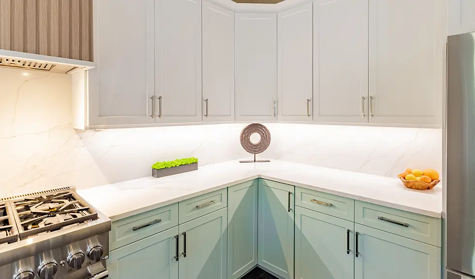 close up of the corner of a two tone kitchen with accents on counter and under cabinet lighting